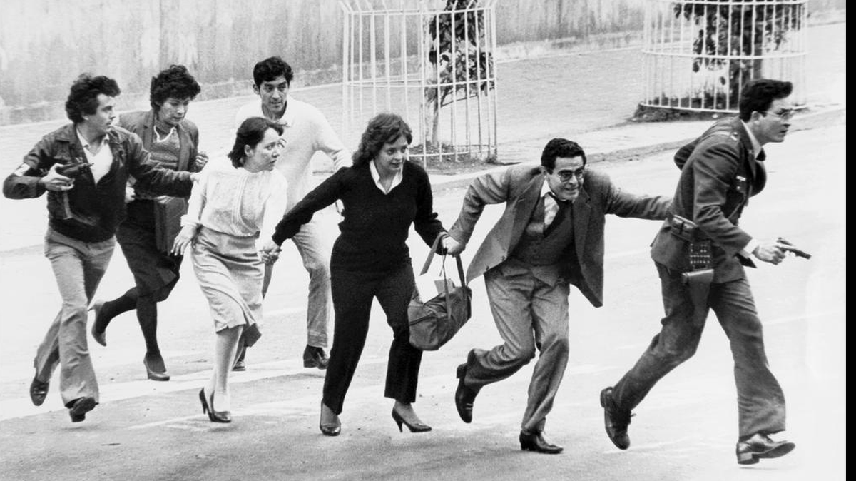 Empleados del Palacio de Justicia de Colombia abandonan el edificio protegidos por policías el 6 de noviembre de 1985 en Bogotá, después que guerrilleros del M-19 lo tomaron.