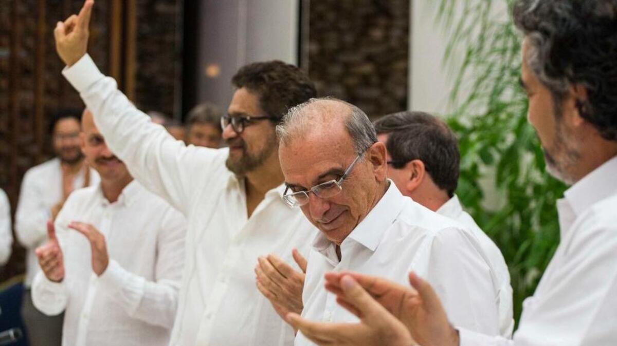 Ivan Márquez, jefe de las FARC (izq.), hace el signo de victoria junto a De La Calle, al firmar acuerdo de paz.