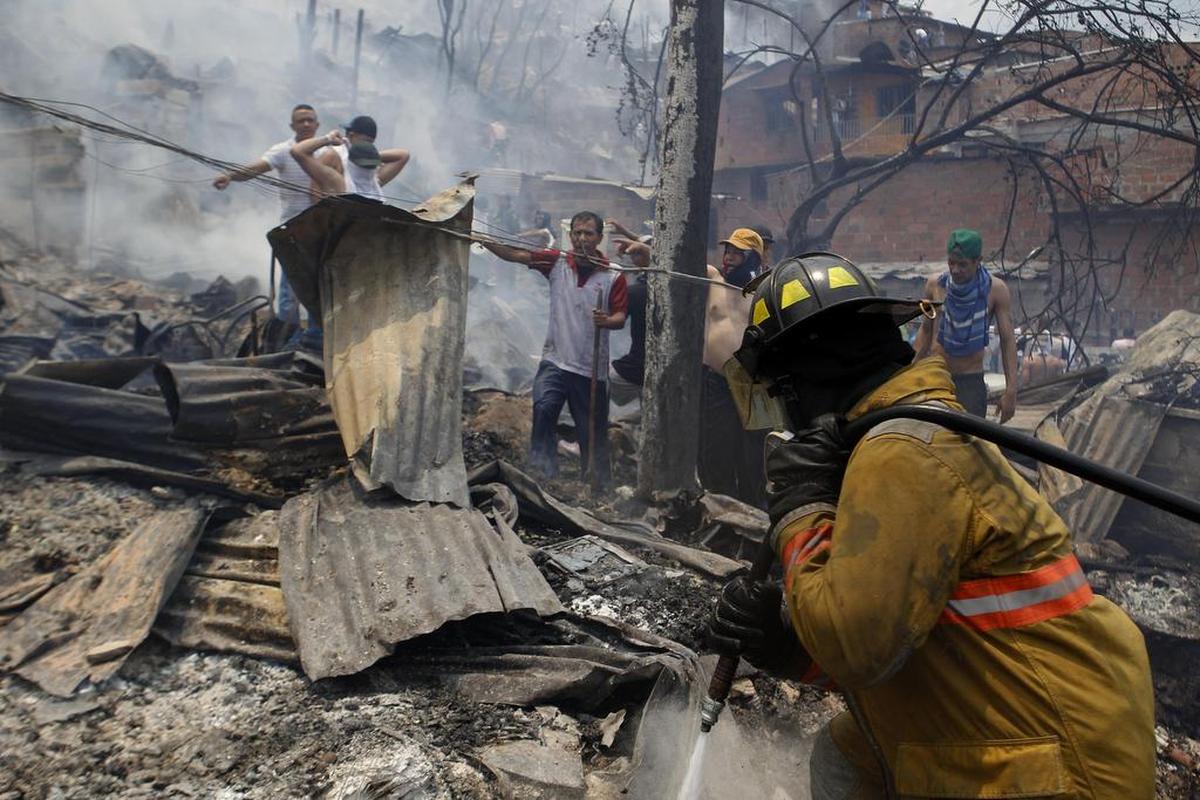 Un bombero intenta apagar un incendio el viernes 18 de agosto de 2107, en el barrio Moravia de Medellín (Colombia).