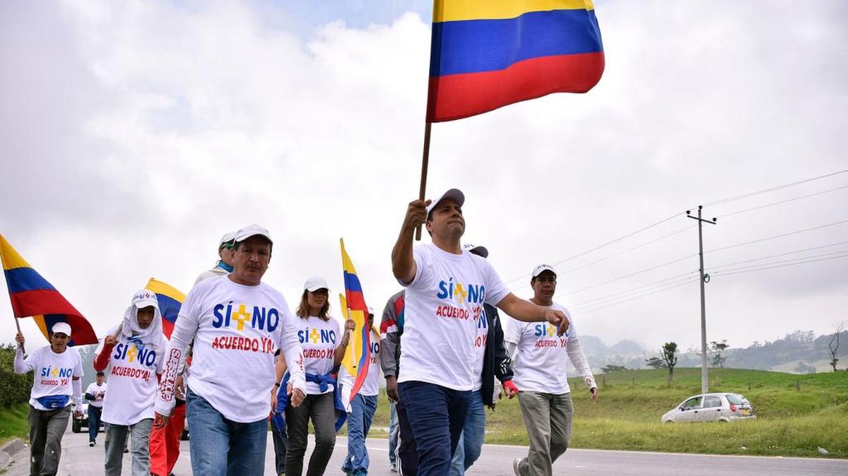 Jhon Jairo Hoyos, al frente, lleva una bandera que lee “Sí + No - un acuerdo ahora!”, marcha desde Calí a Bogotá, acompañado por un grupo de personas, en esta foto del 22 de octubre del 2016.