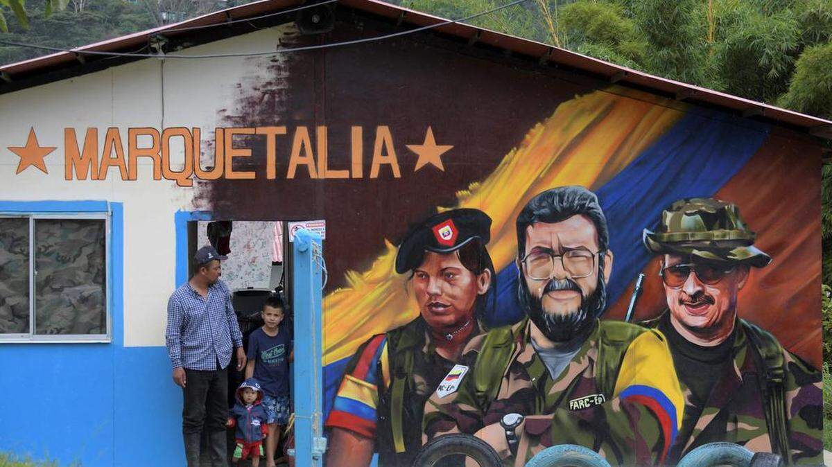 Archivo- En esta foto de archivo tomada el 27 de octubre de 2021, un hombre y niños junto a un grafiti del difunto comandante de las FARC Alfonso Cano (C) en el Área Territorial de Capacitación y Reincorporación (ETCR) El Oso, en Gaitania, Departamento de Tolima, Colombia.