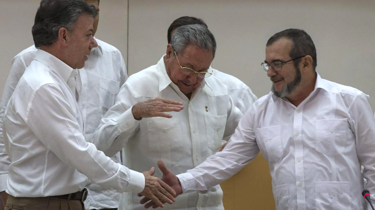 El gobernante de Cuba, Raúl Castro, centro, alienta al presidente colombiano, Juan Manuel Santos, a la izquierda, y el comandante de las Fuerzas Armadas Revolucionarias de Colombia o FARC, Timoleón Jiménez conocido como "Timochenko" a dar la mano, en La Habana, Cuba, Miércoles, 23 de septiembre 2015.