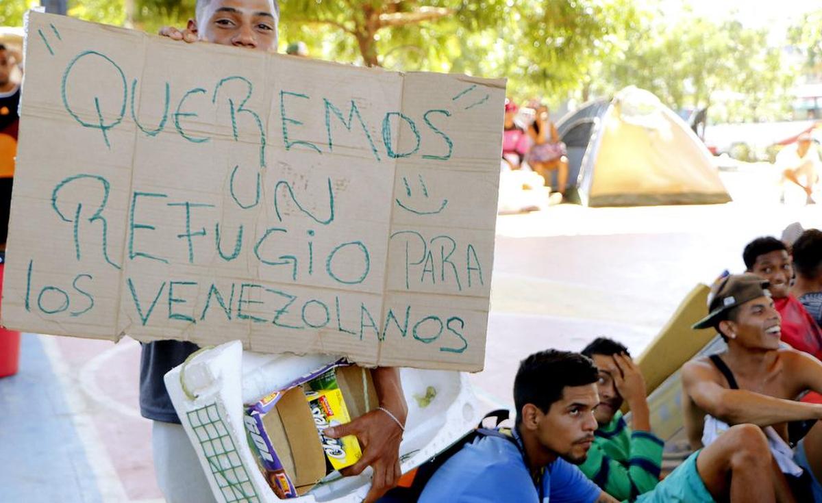 Un venezolano parte del grupo de personas que se tomaron un polideportivo de un barrio de la ciudad de Cúcuta (Colombia) muestra un cartel en el que pide un refugio para sus compatriotas el lunes 22 de enero de 2018.