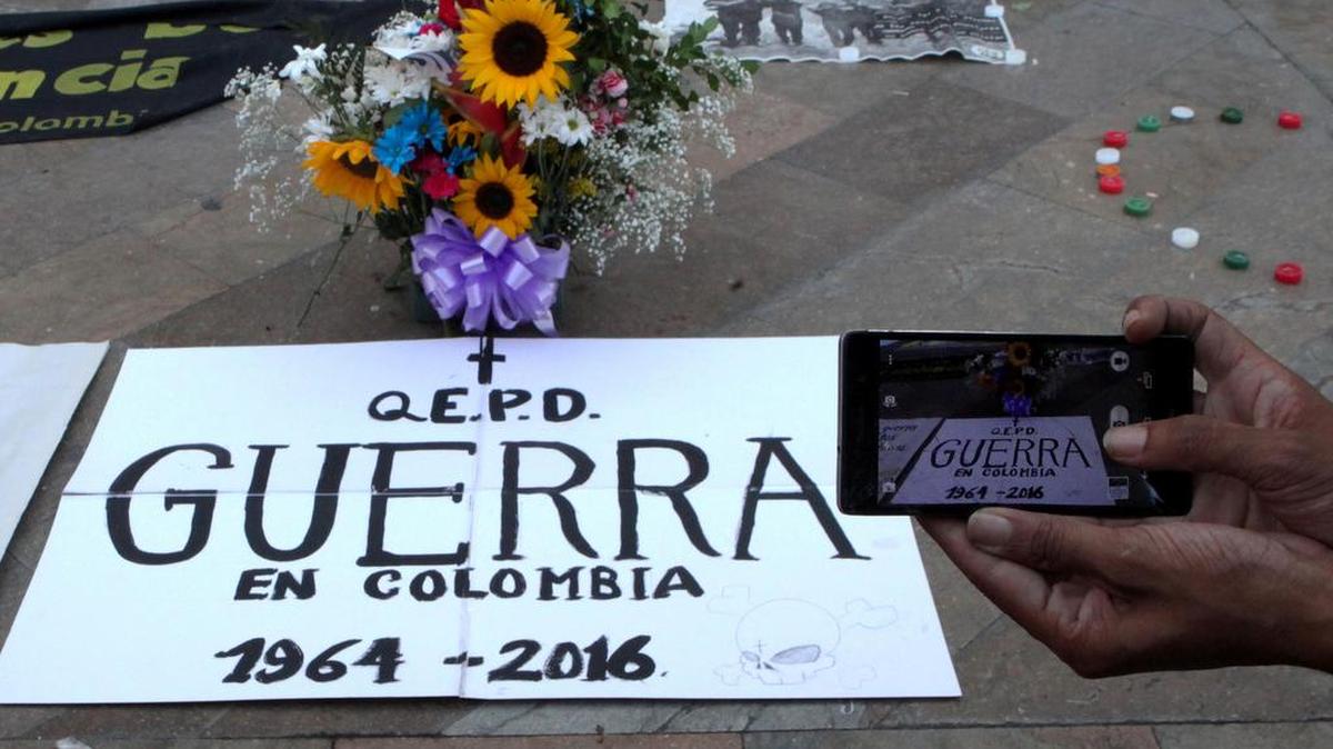Una persona toma fotografías a un cartel durante un acto para celebrar acuerdo de cese el fuego y dejación de armas entre el Gobierno colombiano y la guerrilla de las Fuerzas Armadas Revolucionarias (FARC) el jueves 23 de junio de 2016, en la Plaza Botero de Medellín (Colombia).