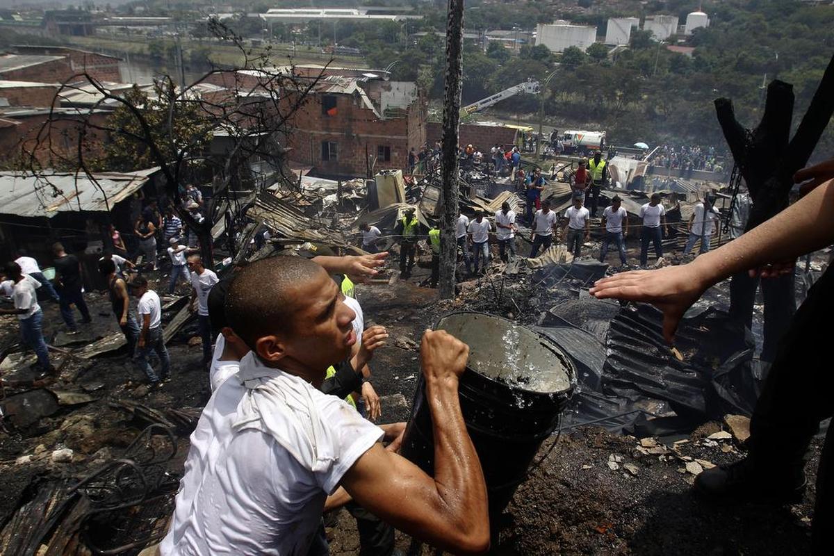 Un grupo de personas intenta apagar un incendio el viernes 18 de agosto de 2107, en el barrio Moravia de Medellín (Colombia).