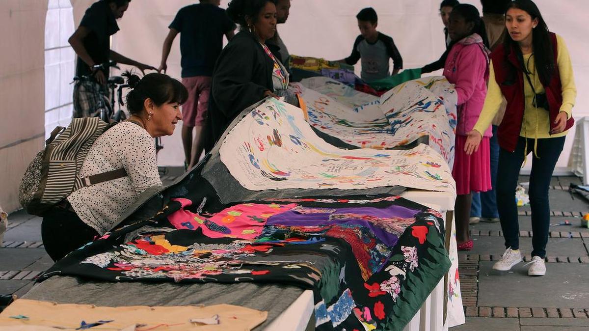 Mujeres víctimas de la violencia y participantes tejen un tapete de mas de 400 metros el domingo 4 de diciembre de 2016, en Bogotá (Colombia).