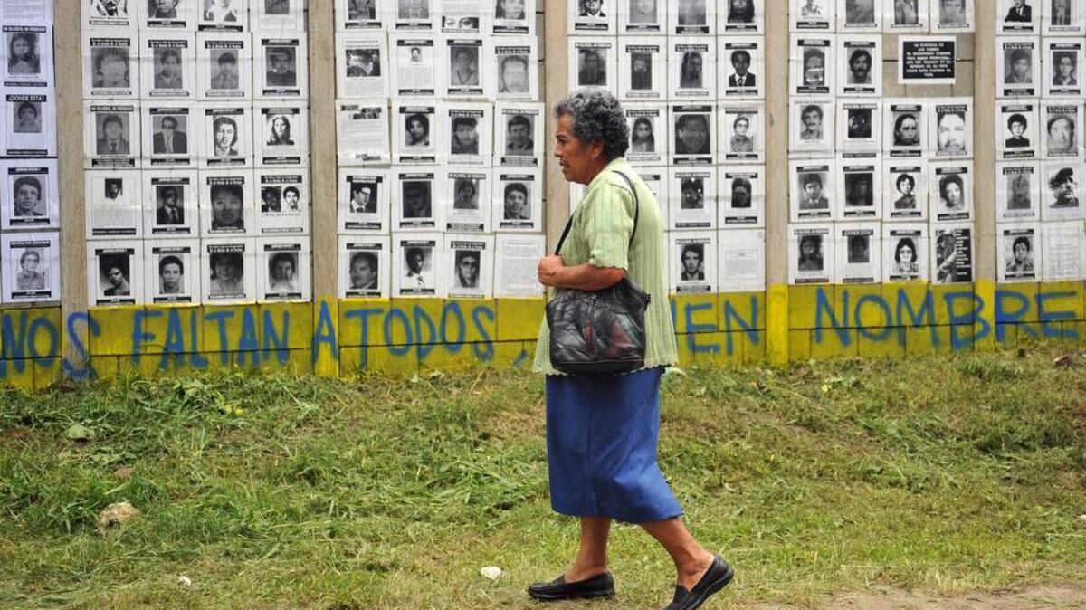 Una mujer pasa frente a un muro donde se exponen fotos de personas desaparecidas durante el sangriento conflicto bélico guatemalteco de 1960 a 1996.