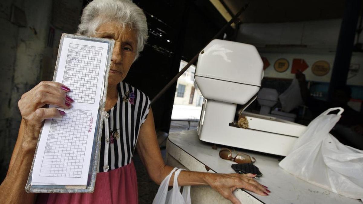
Una anciana muestra su libreta de racionamiento, símbolo de la escasez de alimentos y las dificultades económicas en Cuba.
