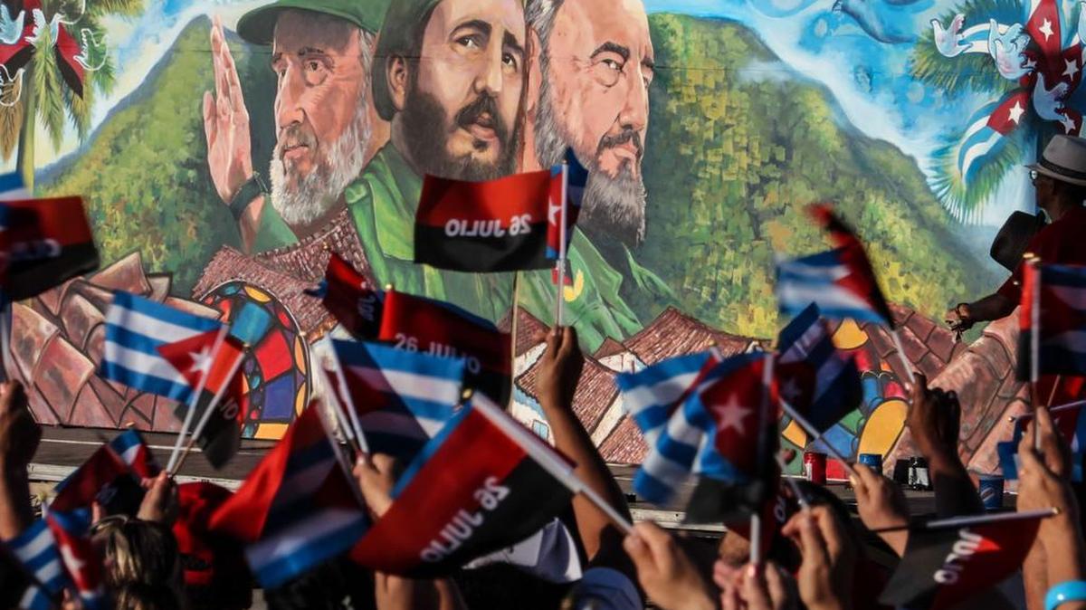 Cubanos agitan banderas frente a un mural de Fidel Castro para celebrar el 26 de julio en Sancti Spíritus, Cuba.