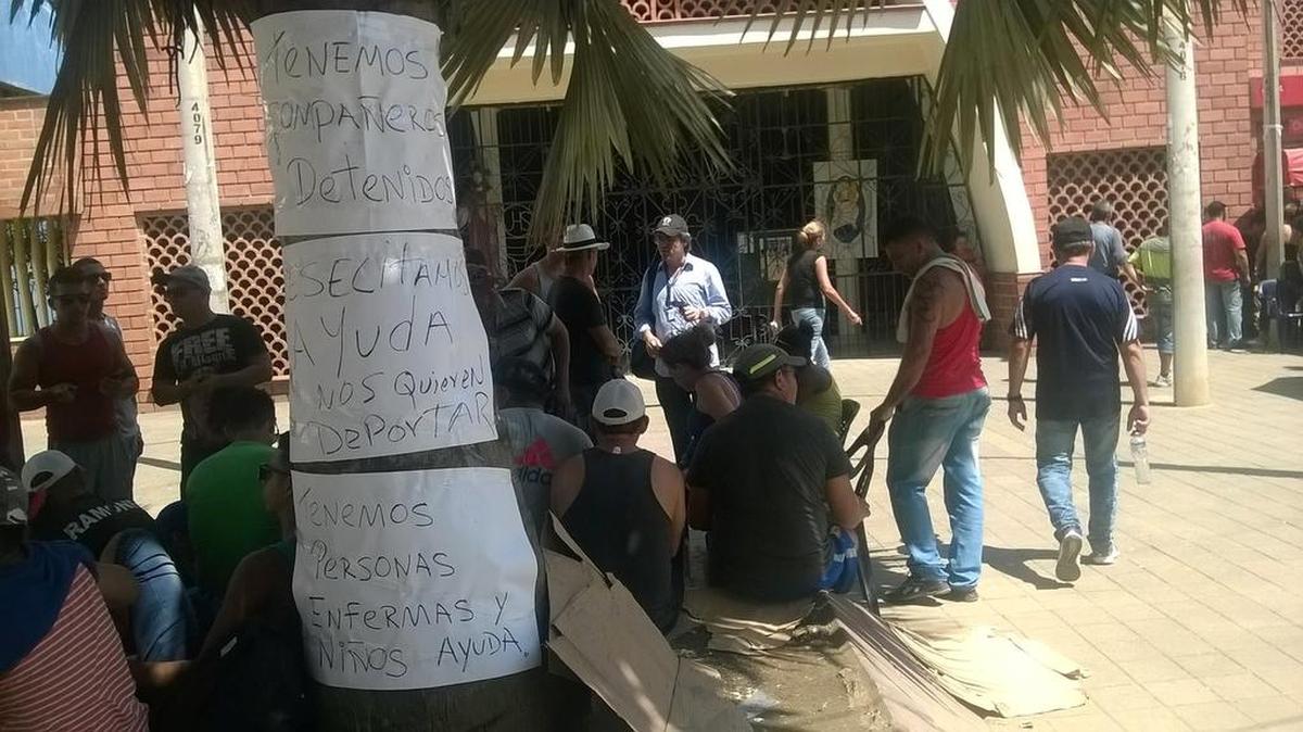 Un grupo de cubanos varados en la ciudad de Turbo, en Colombia, coloca carteles explicando quiénes son y solicitando ayuda.