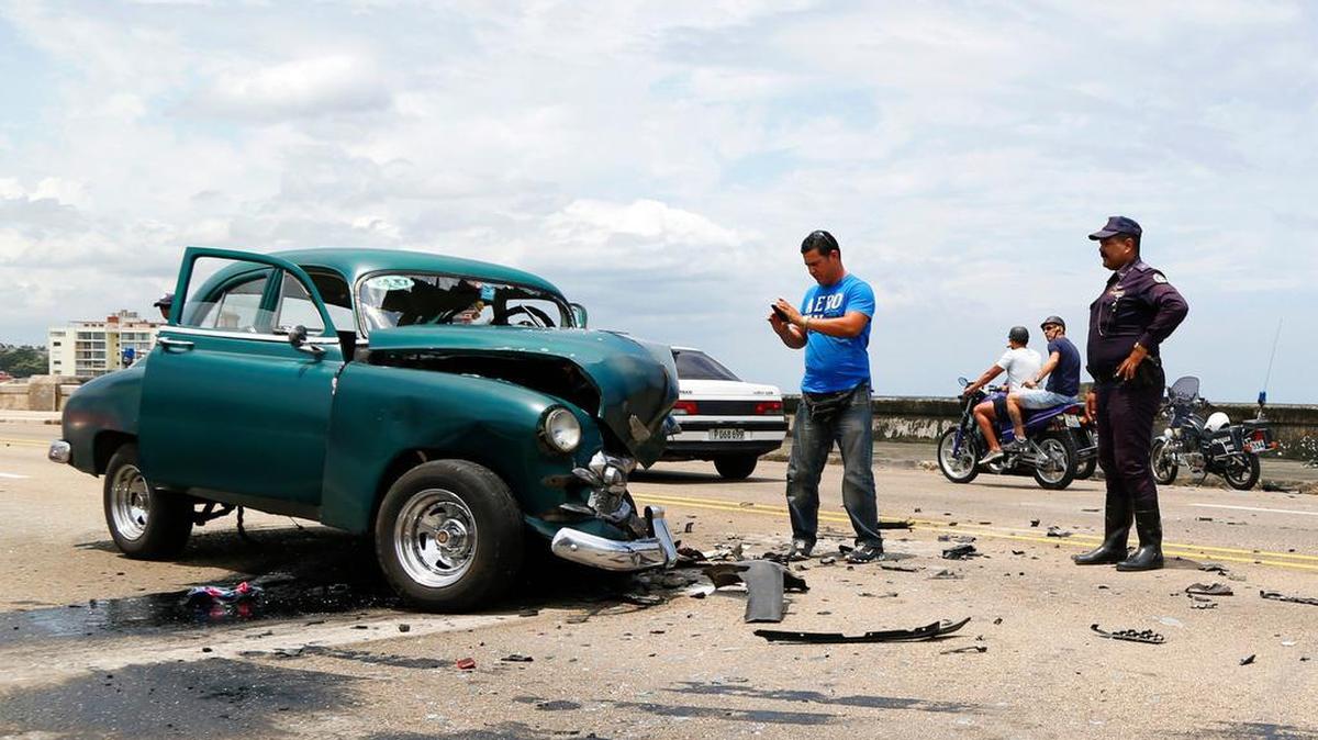 Un hombre toma una foto de un auto que fue dañado en un accidente de tráfico en el Malecón, La Habana, el 4 de mayo del 2015.