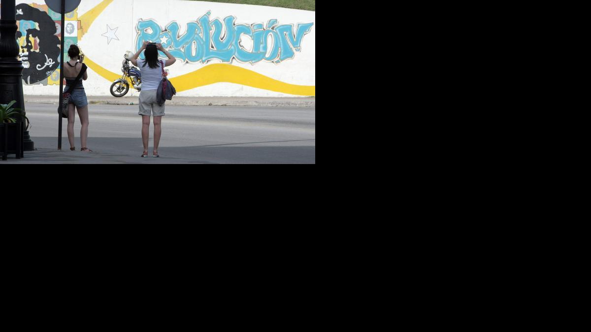 
Fotografía del 26 de diciembre de 2014 de turistas tomando fotos a un grafiti de la revolución cubana en La Habana, Cuba. La nueva relación con Estados Unidos abre para la economía cubana un horizonte de posibilidades, si bien el impacto más inmediato se espera en el sector del turismo con el aumento de visitantes norteamericanos a la isla.
