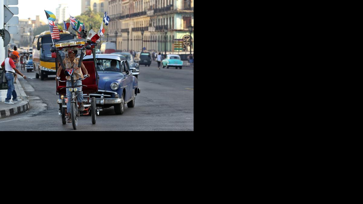
Un bicitaxi adornado con varias banderas, entre ellas una de Estados Unidos , circula por una calle de La Habana (Cuba), el martes 31 de marzo de 2015. 
