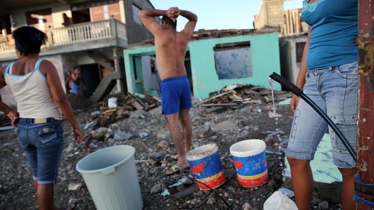 Cubanos recolectan agua el viernes 7 de octubre de 2016, tras el paso hace tres días del huracán Matthew en Baracoa (Cuba).