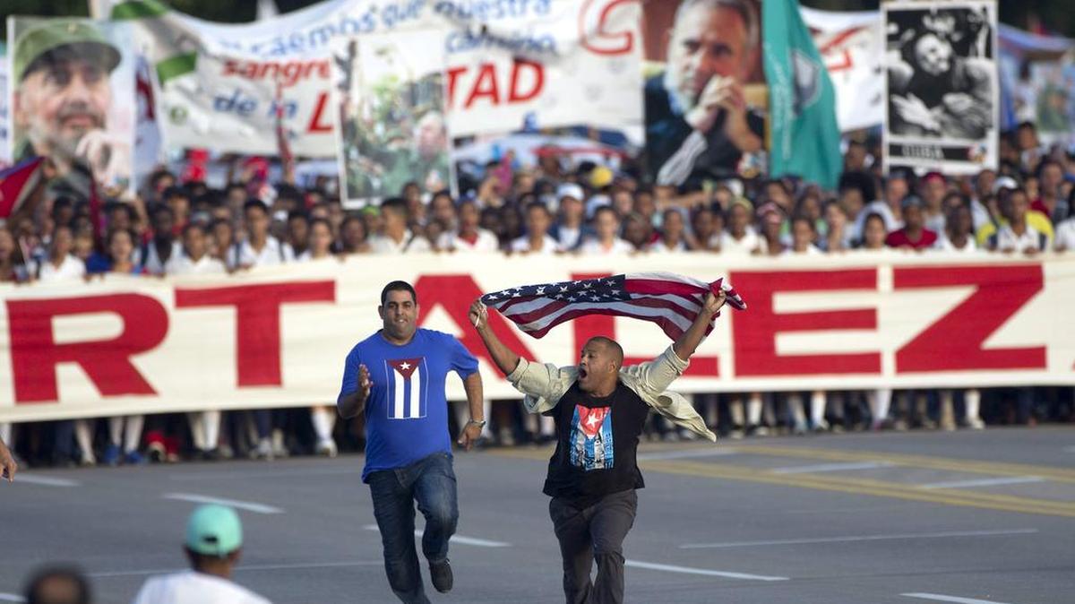 Un oficial de la seguridad persigue a un hombre agitando una bandera de Estados Unidos momentos antes del inicio de la marcha del primero de mayo en La Habana, Cuba, el lunes 1o de mayo de 2017.