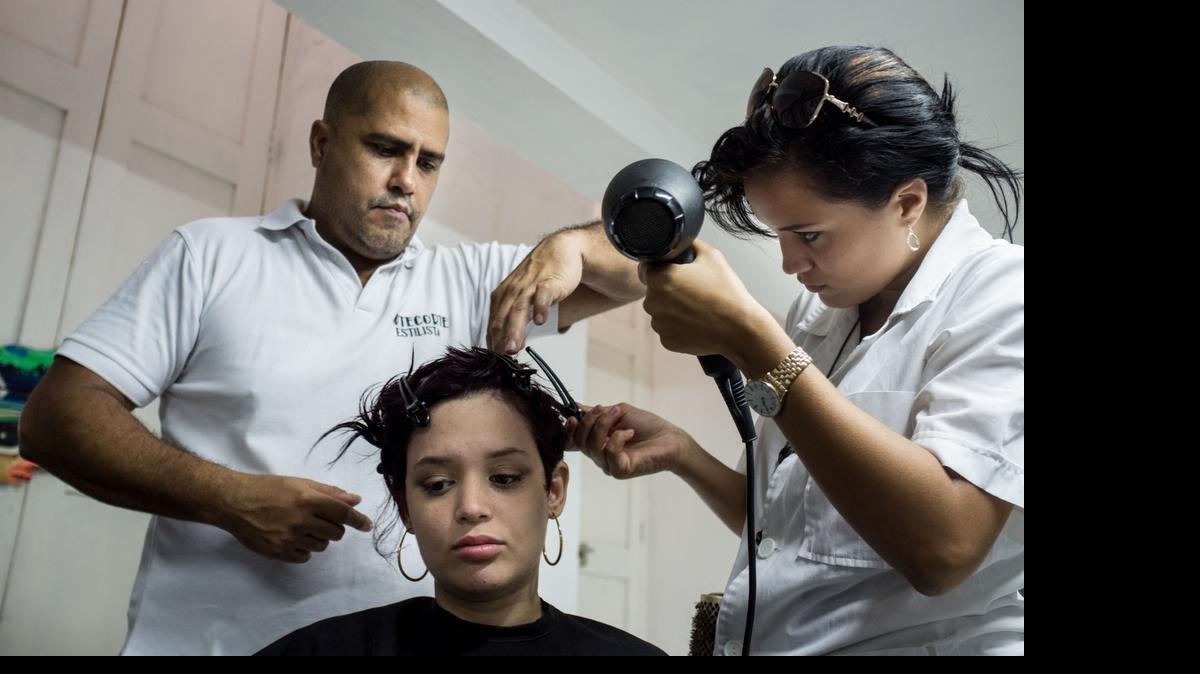 
Gilberto Valladares supervisa a uno de los alumnos que entrena en su peluquería como una forma de brindar un servicio social en un barrio pobre de La Habana.
