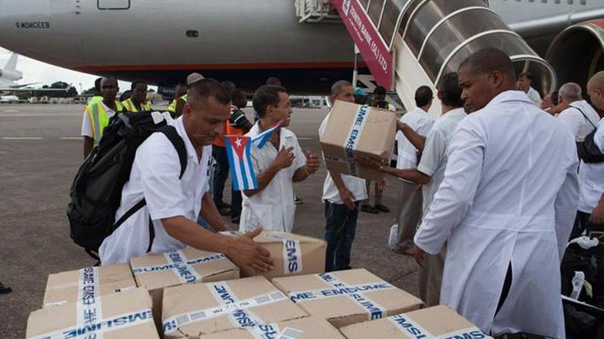Los primeros miembros de un equipo de 165 médicos y trabajadores de salud cubanos descargan cajas de medicamentos y material médico de un avión a su llegada al aeropuerto de Freetown para ayudar a la lucha contra el ébola en Sierra Leona.