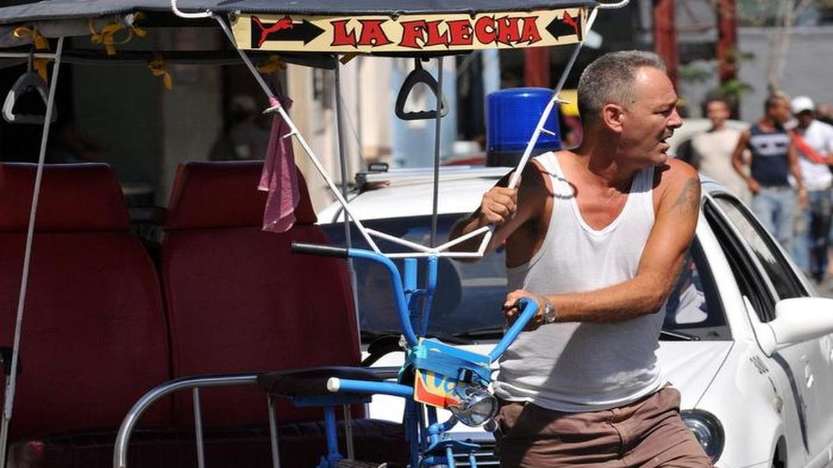 El conductor de un bicitaxi camina junto a su vehículo en La Habana.