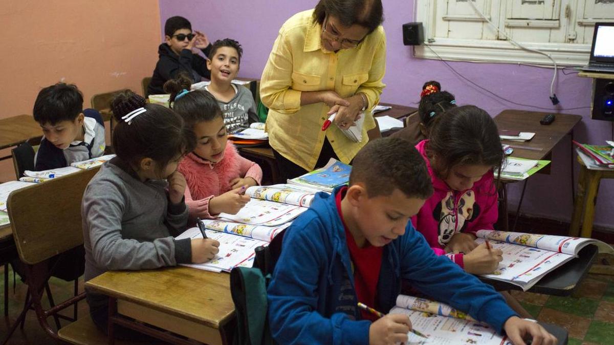 La maestra Graciela Lage ayuda a estudiantes durante una clase de inglés een la Escuela de Lenguas Extranjeras en La Habana.