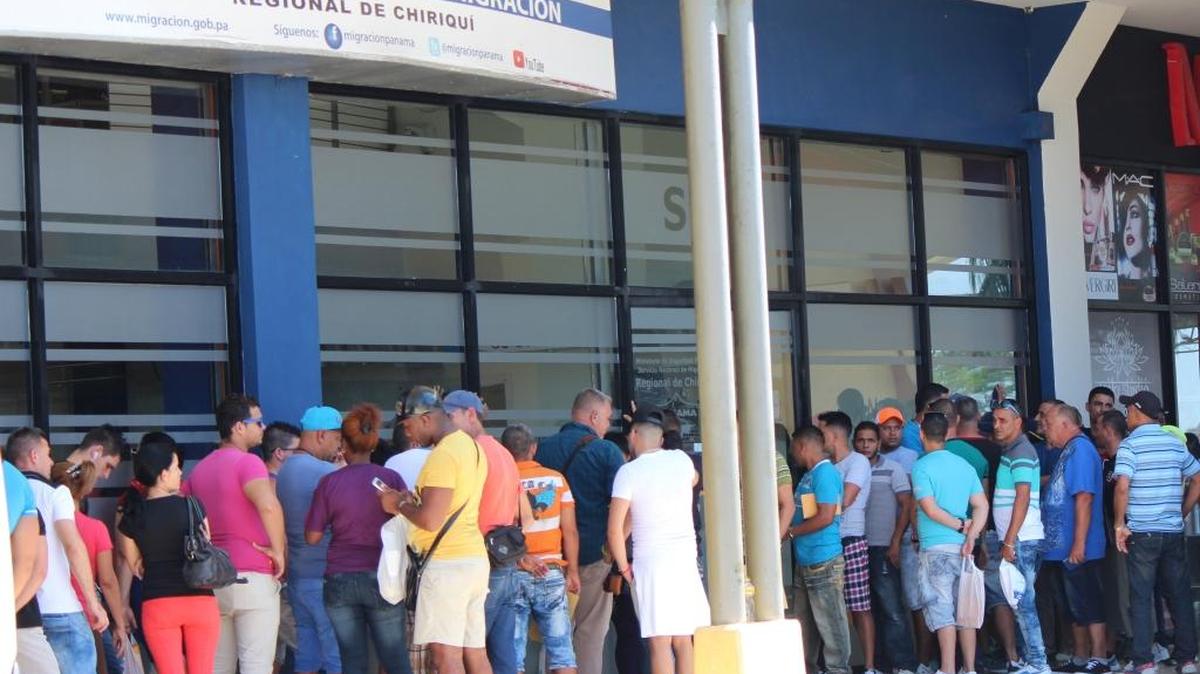 Migrantes cubanos esperan para recibir en sus pasaportes un permiso migratorio para poder salir legalmente de Panamá hacia México, desde donde cruzarán a Estados Unidos.