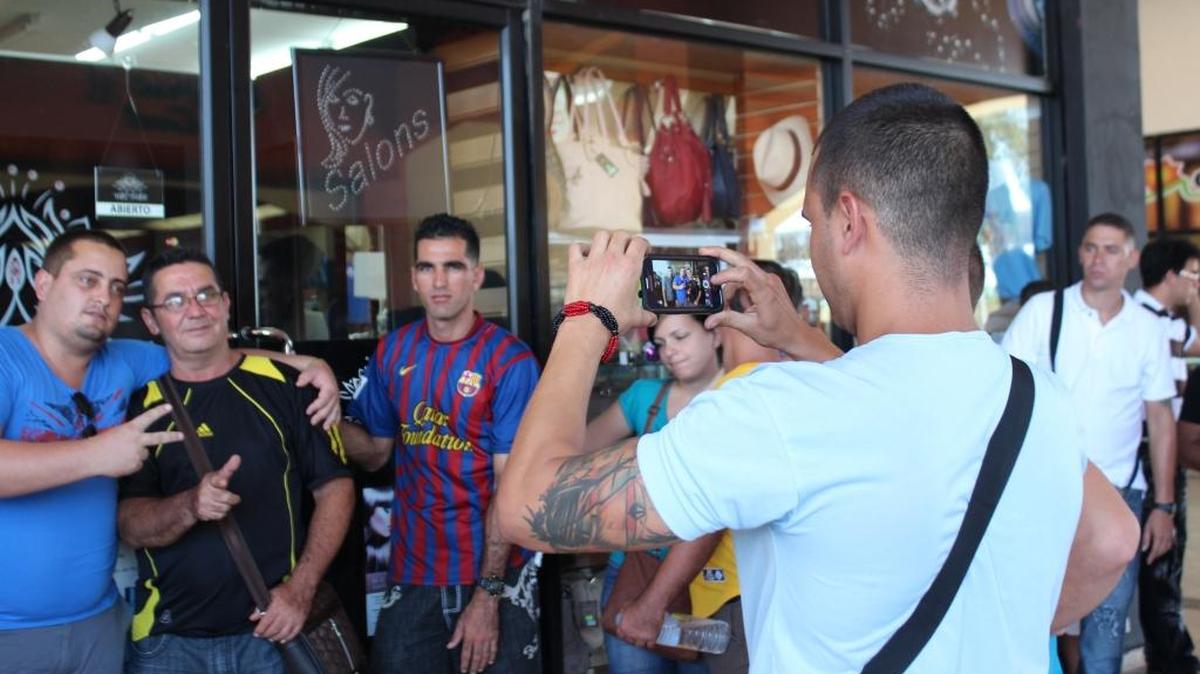 Migrantes cubanos se toman fotografías mientras esperan el domingo frente a las puertas de la oficina de Migración de David, para recibir en sus pasaportes un permiso migratorio para poder salir legalmente de Panamá hacia México, desde donde cruzarán a Estados Unidos.
