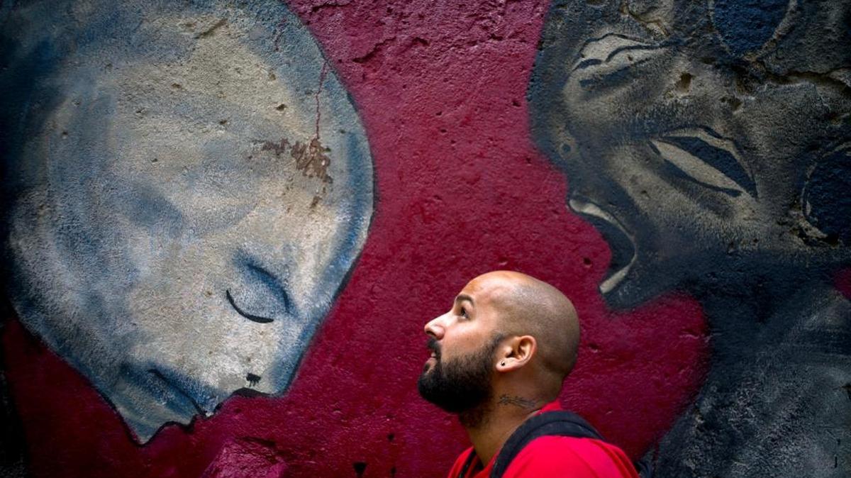 En esta foto del 9 de febrero de 2017, el artista de graffiti Yulier Rodríguez Pérez posa con una de sus obras, pintada en una pared de La Habana Vieja, Cuba. Hace tres años, los caprichosos diseños del artista de 27 años con la firma Yulier P. comenzaron a aparecer en las paredes de La Habana donde el graffiti es raro.