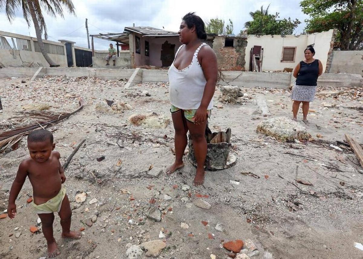 Esperanza Reyes (centro), su hijo Michael, de 2 años, y una mujer no identificada, Vecinos del poblado costero de Jaimanitas, observan a los pescadores trabajando, el 28 de septiembre del 2017, junto a viviendas dañadas por el huracán Irma.
