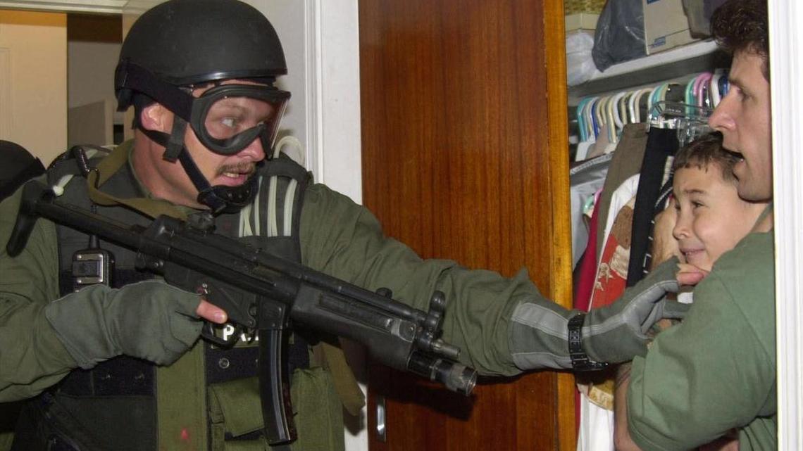 Elián González es sostenido por Donato Dalrymple, mientras oficiales del gobierno buscan al pequeño en la casa de Lázaro Gonzalez el sábado 22 de abril de 2000 en Miami.