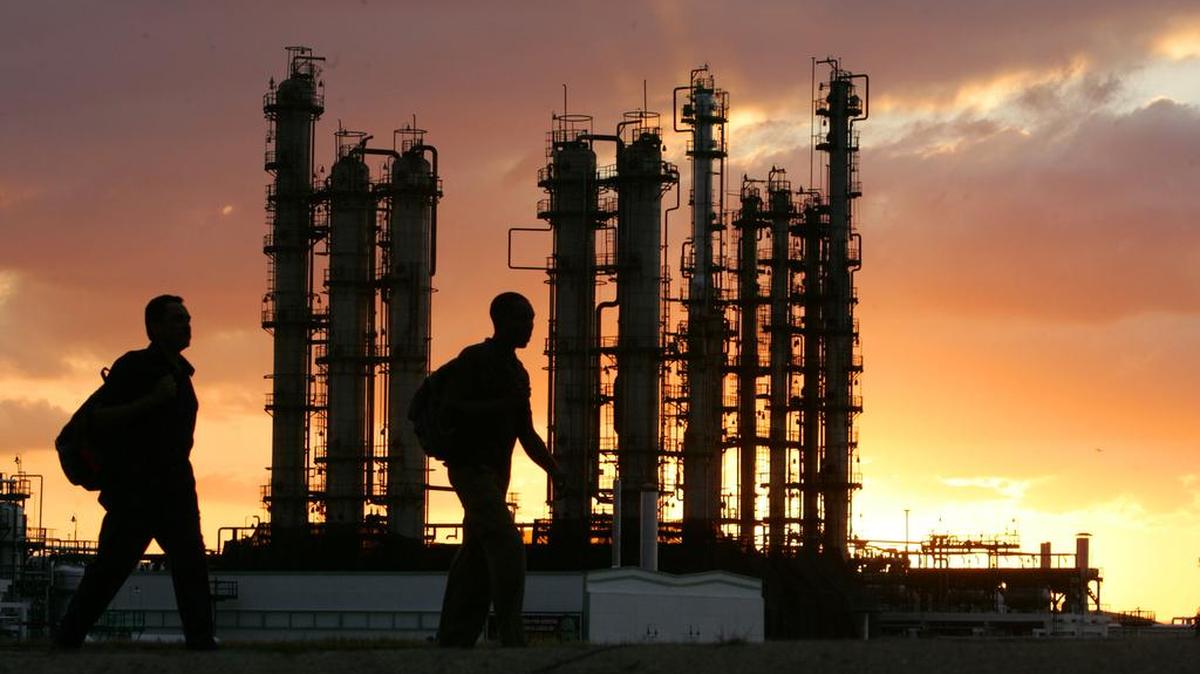 Trabajadores cubanos caminan junto a la refinería de petróleo Camilo Cienfuegos, en Cienfuegos, en diciembre del 2007, reconstruida parcialmente con financiamiento de Venezuela. 