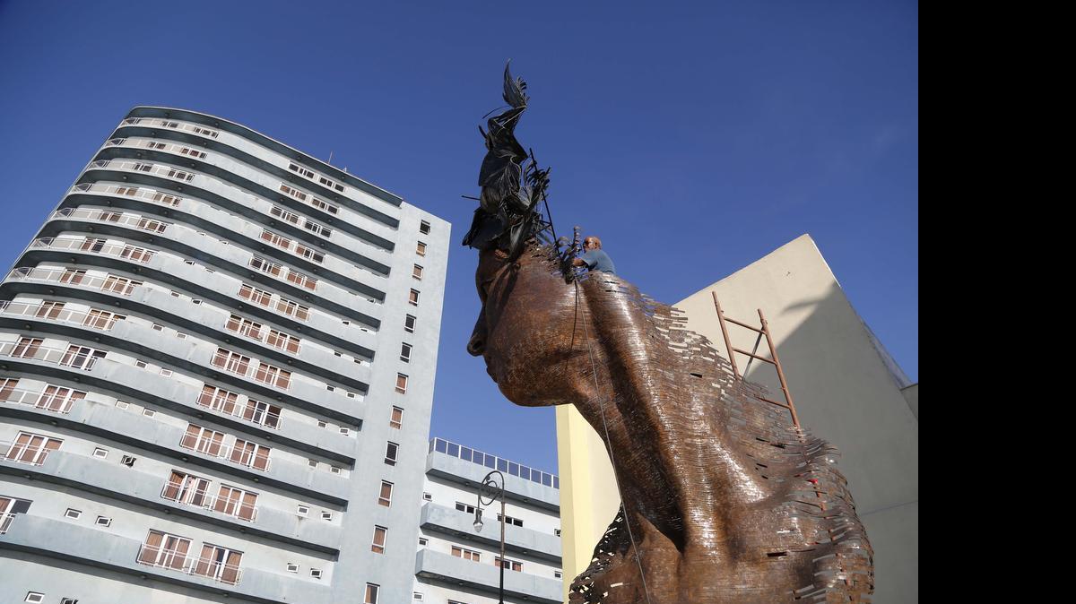 
Un hombre da los toques finales a una creación dedicata a la mujer cubana, del artista Rafael San Juan en La Habana.
