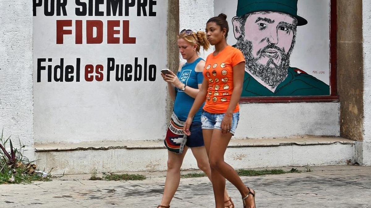 Dos jóvenes pasan frente a un cartel con la imagen de Fidel Castro, el 13 de agosto del 2017, en La Habana.