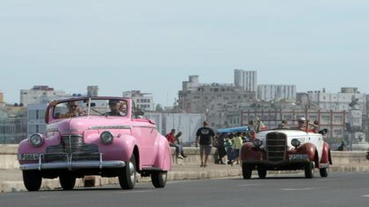 
Fotografía del 26 de diciembre de 2014 de varios turistas paseando por el malecón en dos autos antiguos en La Habana, Cuba. 