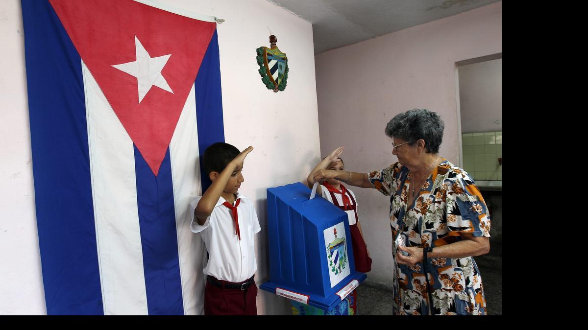 
Una mujer vota mientras niños custodian las urnas hoy, domingo 19 de abril de 2015, durante las elecciones para la designación de delegados de asambleas locales (concejales), en La Habana (Cuba). 
