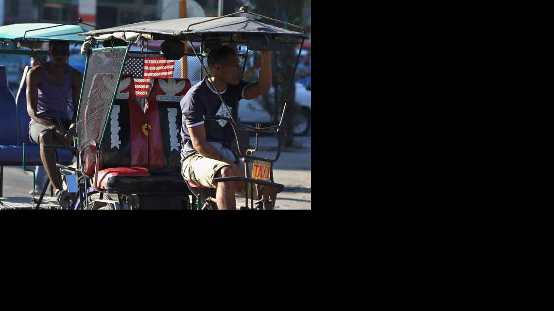 
Un bicitaxista con la bandera de EE.UU. decorando su vehículo espera la llegada de clientes el jueves 18 de diciembre de 2014, en La Habana (Cuba). Los medios oficiales de Cuba dedican sus principales titulares al regreso de los tres agentes cubanos que permanecían presos en EE.UU., a la vez que publican íntegros los discursos de los presidentes de Cuba, Raúl Castro, y de Estados Unidos, Barack Obama, anunciando el restablecimiento de relaciones diplomáticas.
