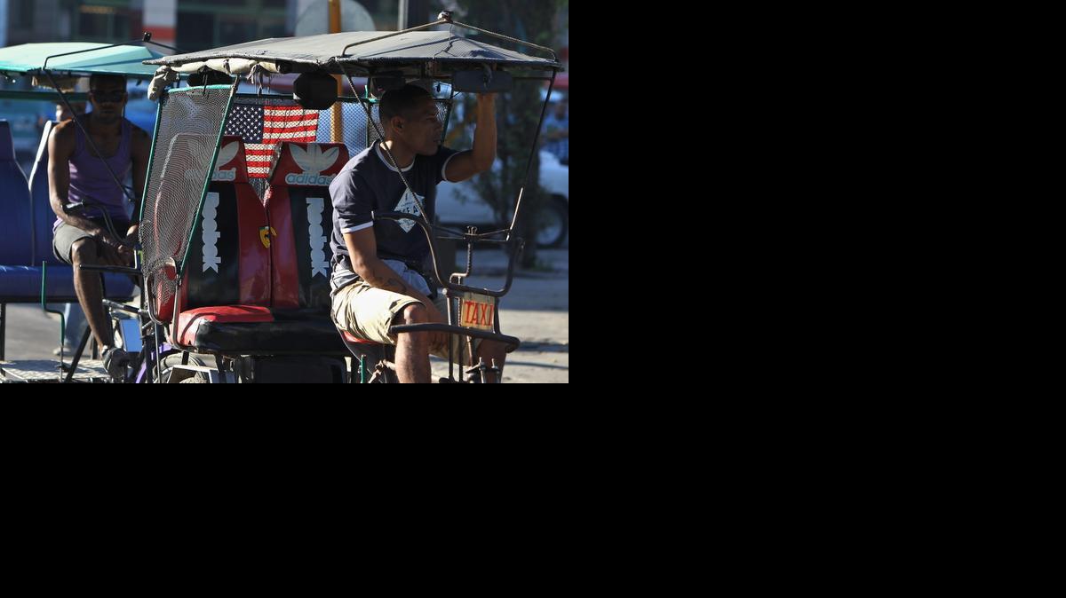 
Un bicitaxista con la bandera de EE.UU. decorando su vehículo espera la llegada de clientes el jueves 18 de diciembre de 2014, en La Habana (Cuba). Los medios oficiales de Cuba dedican sus principales titulares al regreso de los tres agentes cubanos que permanecían presos en EE.UU., a la vez que publican íntegros los discursos de los presidentes de Cuba, Raúl Castro, y de Estados Unidos, Barack Obama, anunciando el restablecimiento de relaciones diplomáticas.
