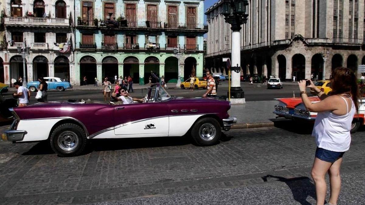 Una turista argentina se retrata en un automóvil clásico en La Habana, en foto de archivo.