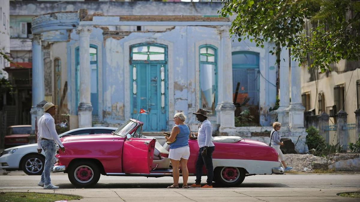 Un turista habla con los lugareños junto a un viejo automóvil estadounidense en La Habana, el 31 de marzo de 2017.