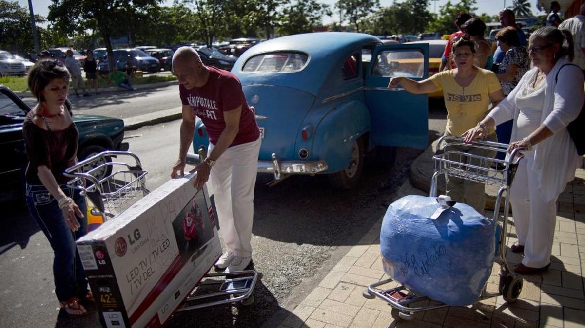A man prepares to lift a large TV to a private taxi cab as he helps a traveler who arrived from the U.S. at the José Martí International Airport in Havana, Cuba.