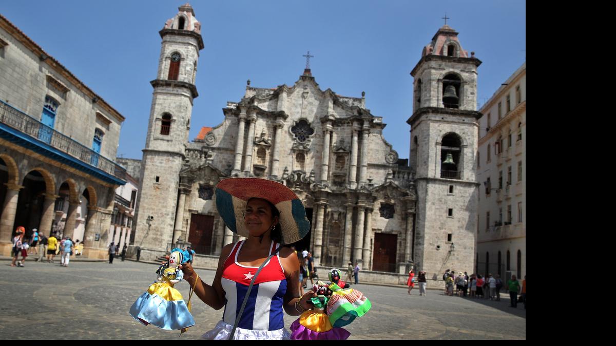 
Una mujer vestida con la bandera cubana vende muñecas en la Plaza de la Catedral de La Habana.
