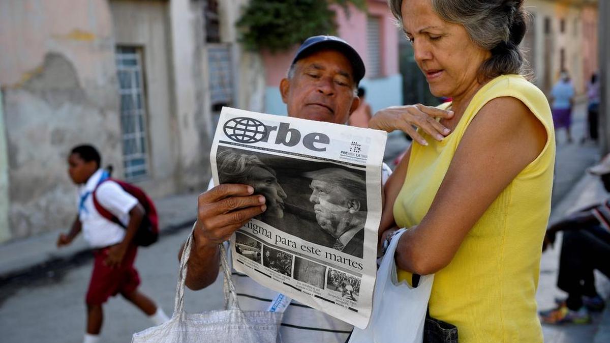 Dos cubanos leen un periódico oficial donde en la tapa se puede ver un reportaje sobre las elecciones estadounidenses, el 9 de noviembre en La Habana, Cuba.