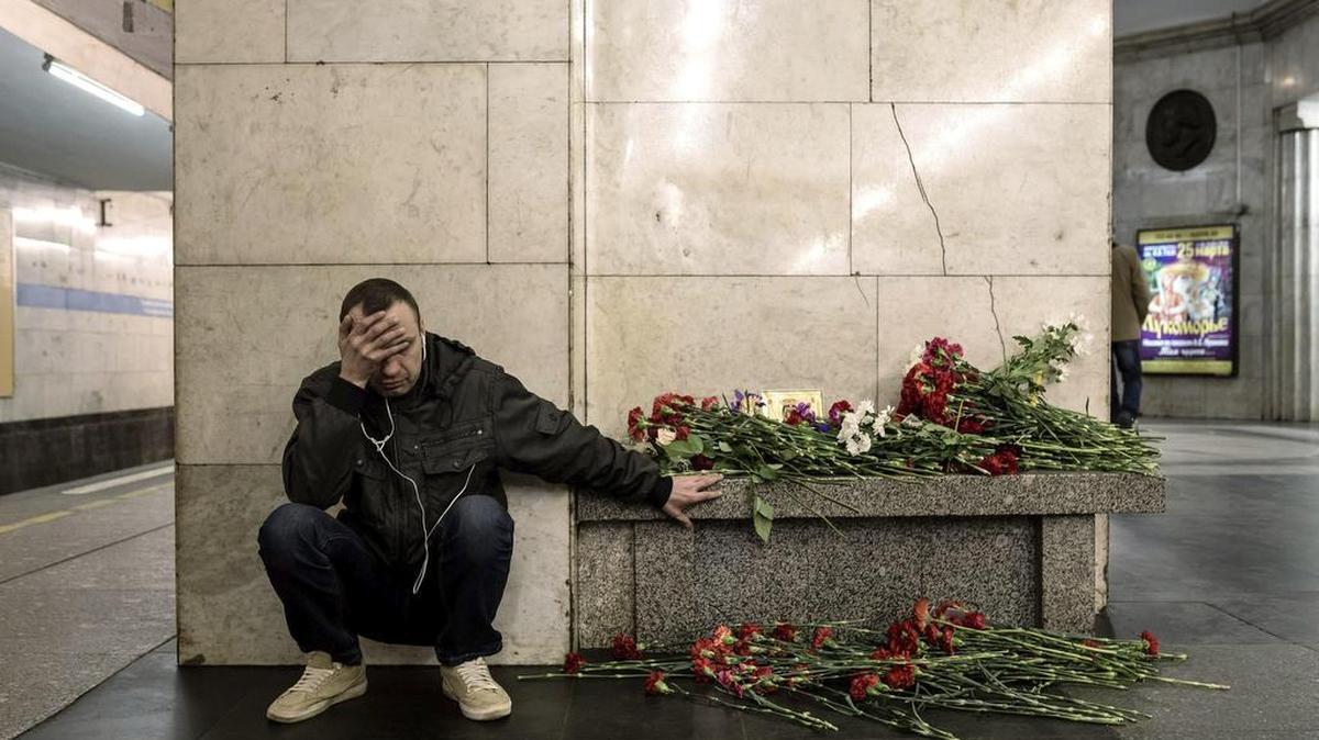 Un hombre llora junto a un banco lleno de flores en un andén de la estación de metro Tejnologuícheskiy Institut, en memoria de las víctimas del atentado, en San Petersburgo (Rusia) el 4 de abril de 2017, un día después del ataque.