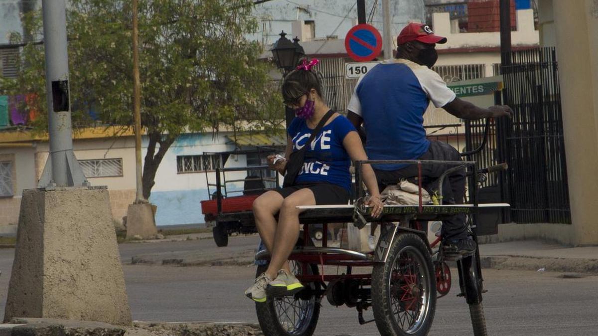 Una mujer viaja en la parte trasera de un triciclo que se usa comúnmente para transportar carga en La Habana, Cuba, el lunes 27 de diciembre de 2021 (AP Foto / Ismael Francisco).