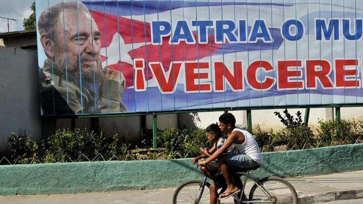 
Foto de archivo. Jóvenes cubanos pasan en bicicleta frente a una valla con la imagen del ex gobernante Fidel Castro, en La Habana, Cuba.