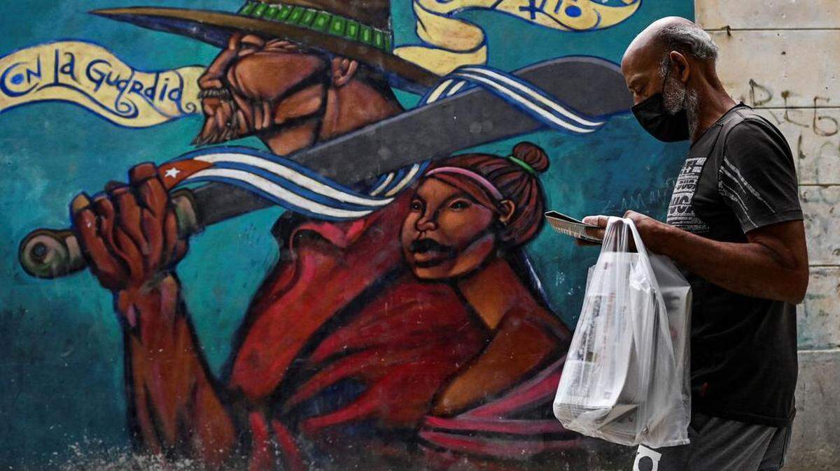 Un hombre con mascarilla pasa junto a un grafiti en La Habana, el 11 de noviembre de 2021.