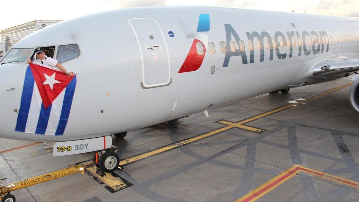 Kevin Mase, de American Airlines, saca una bandera cubana por la ventanilla de un AA Boeing 737, en diciembre del 2015.
