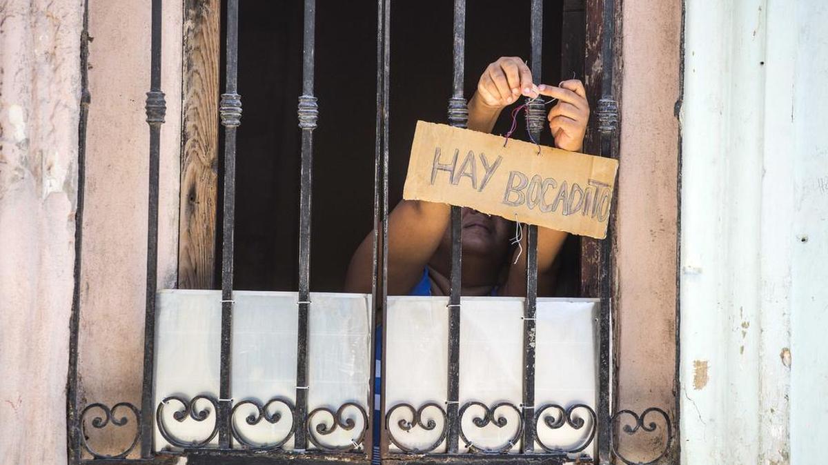Una mujer cuelga en su ventana un letrero qu dice ‘Hay bocadito’, en La Havana, Cuba, el 24 de mayo del 2016.