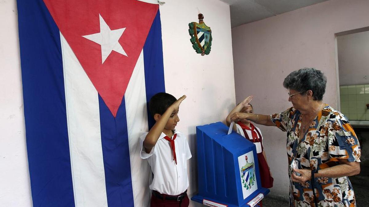 Una mujer vota mientras niños custodian las urnas de votación el 19 de abril de 2015, durante las elecciones para la designación de delegados de asambleas locales (concejales), en La Habana (Cuba).