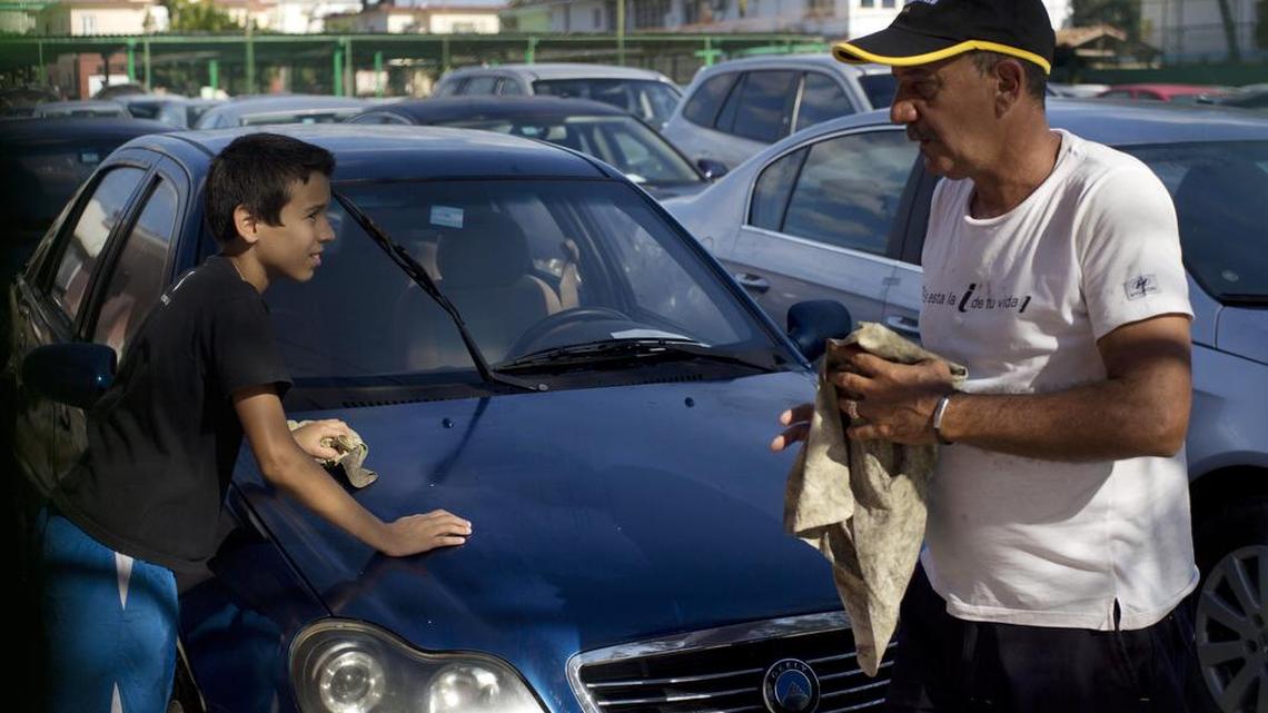 Un empleado limpia un auto de fabricación china en un consecionario estatal en La Habana, Cuba.