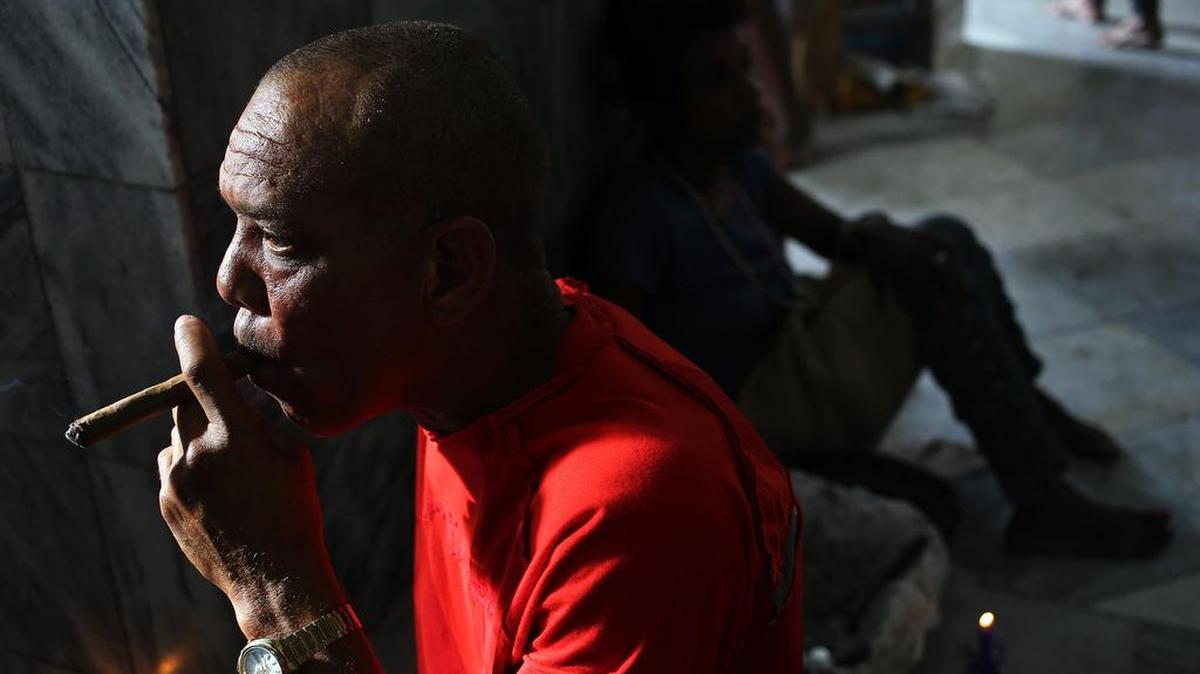 Un hombre fuma un tabaco en homenaje a San Lázaro el viernes 16 de diciembre de 2016, en el Santuario de El Rincón, en La Habana (Cuba). 