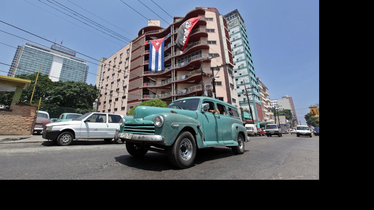 
Un auto pasa frente a un edificio donde se expone la bandera cubana y la del movimiento del 26 julio hoy, martes 21 de julio de 2015, en La Habana (Cuba), un día después de la apertura de la Embajada de estados Unidos en la Isla.
